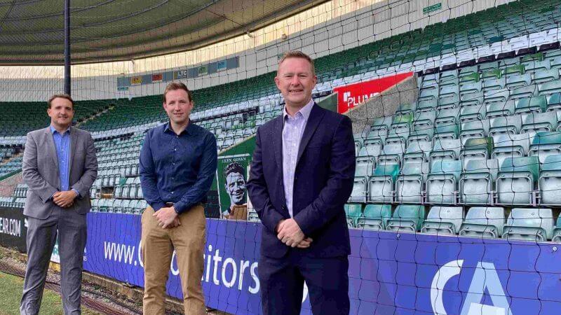 James Peterson, James Greenacre and James Walsh standing on the Plymouth Argyle FC football pitch next to the stands