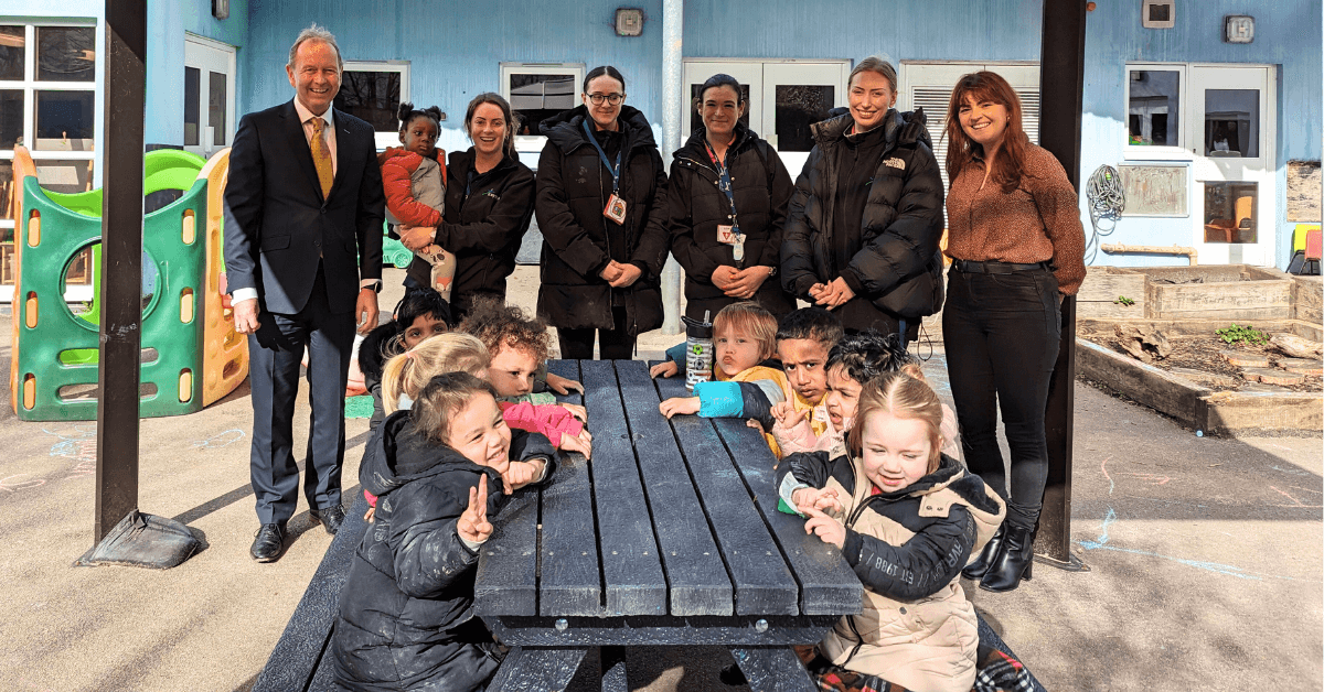 GA Solicitors Team Members standing in front of a weatherproof picnic bench with kids sat at it